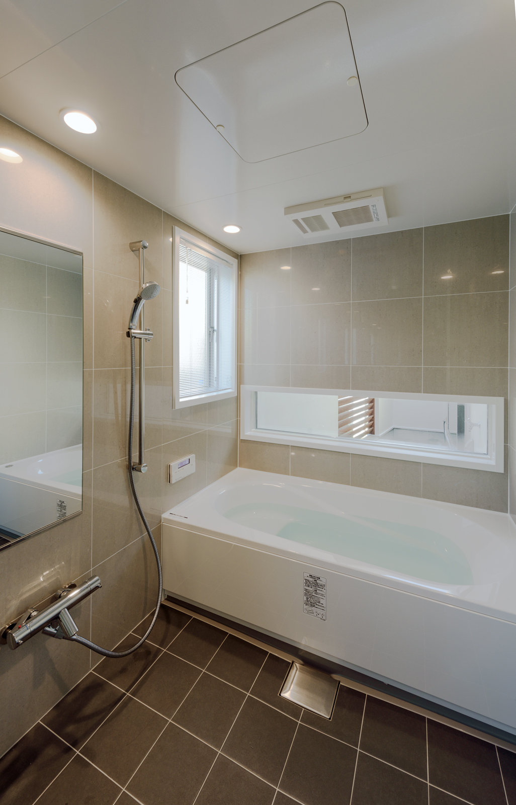 壁と床がタイル張りの高級感あるバスルーム
床のタイルは洗面スペースと同じタイルを用いており、空間の一体感が感じられます
浴槽の奥にある横長の窓からは、中庭の景色を楽しむことができます